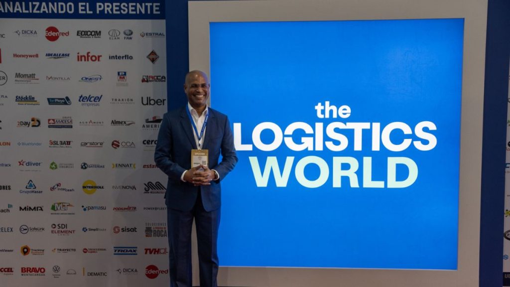 Marco Jensen frente al cartel principal de The Logistics World 2024, con gafete de speaker.