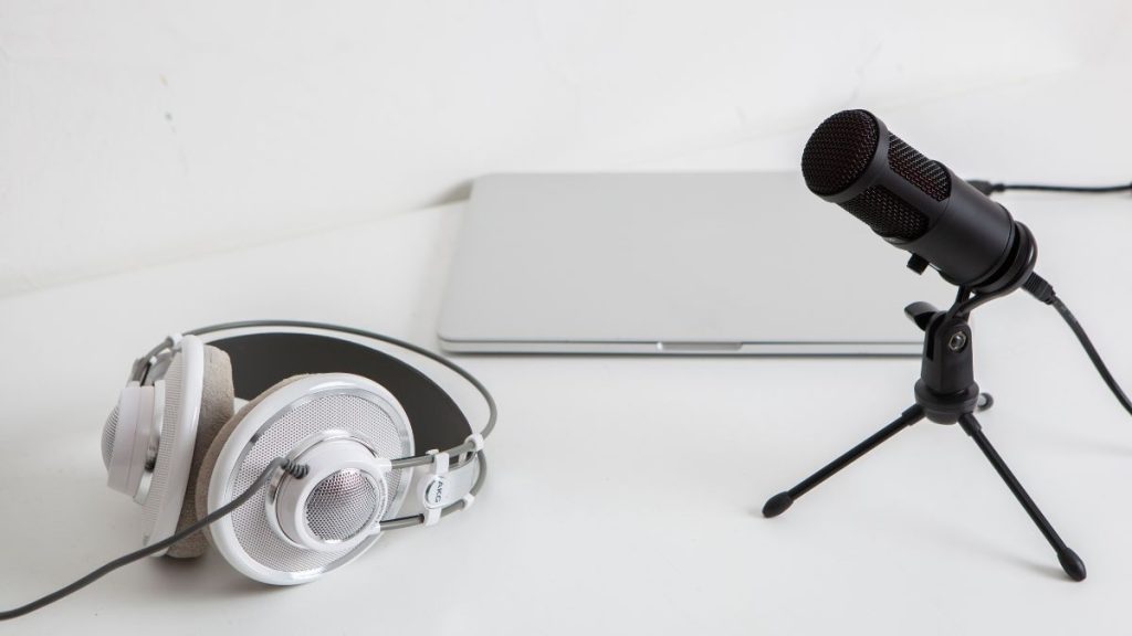 Micrófono profesional, audífonos y una laptop sobre un escritorio, listos para grabar un podcast o video.